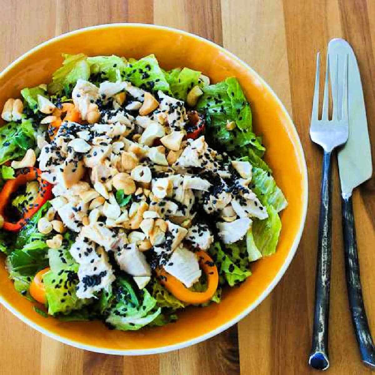 Asian Chopped Chicken Salad shown in serving bowl with knife and fork.