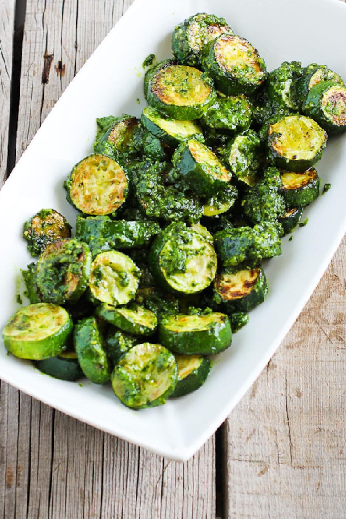 Zucchini with Pesto on serving platter sitting on wooden table