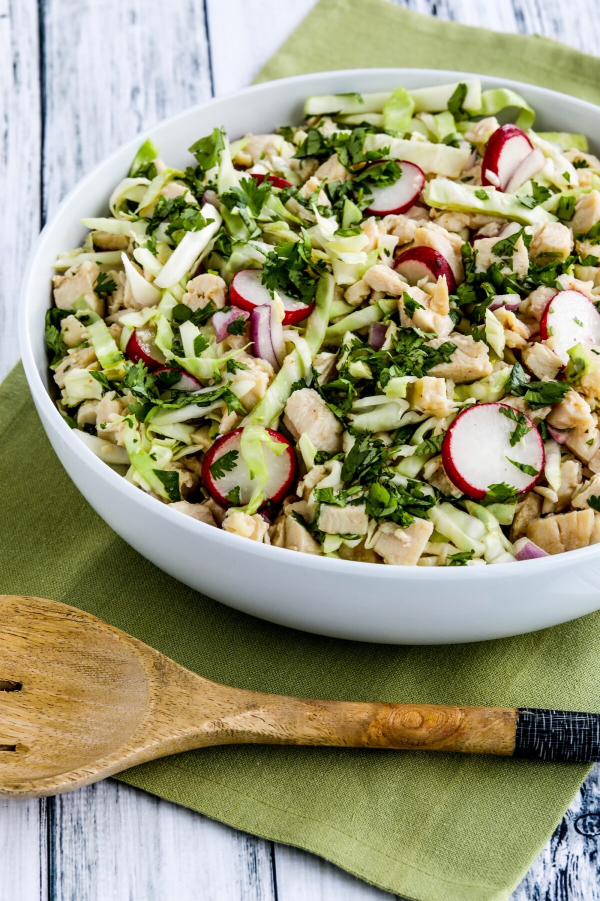 Vietnamese Chicken Salad with Cabbage in serving bowl with napkin and large serving spoon