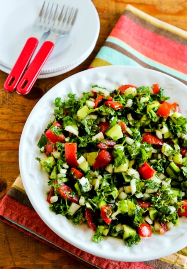 Middle Eastern Tomato Salad on serving plate with plates and forks in back.