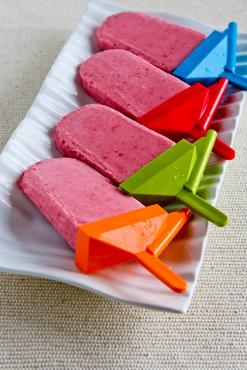 Low-Sugar Strawberry Frozen Yogurt Pops show on plate with popsicle stick mold attached