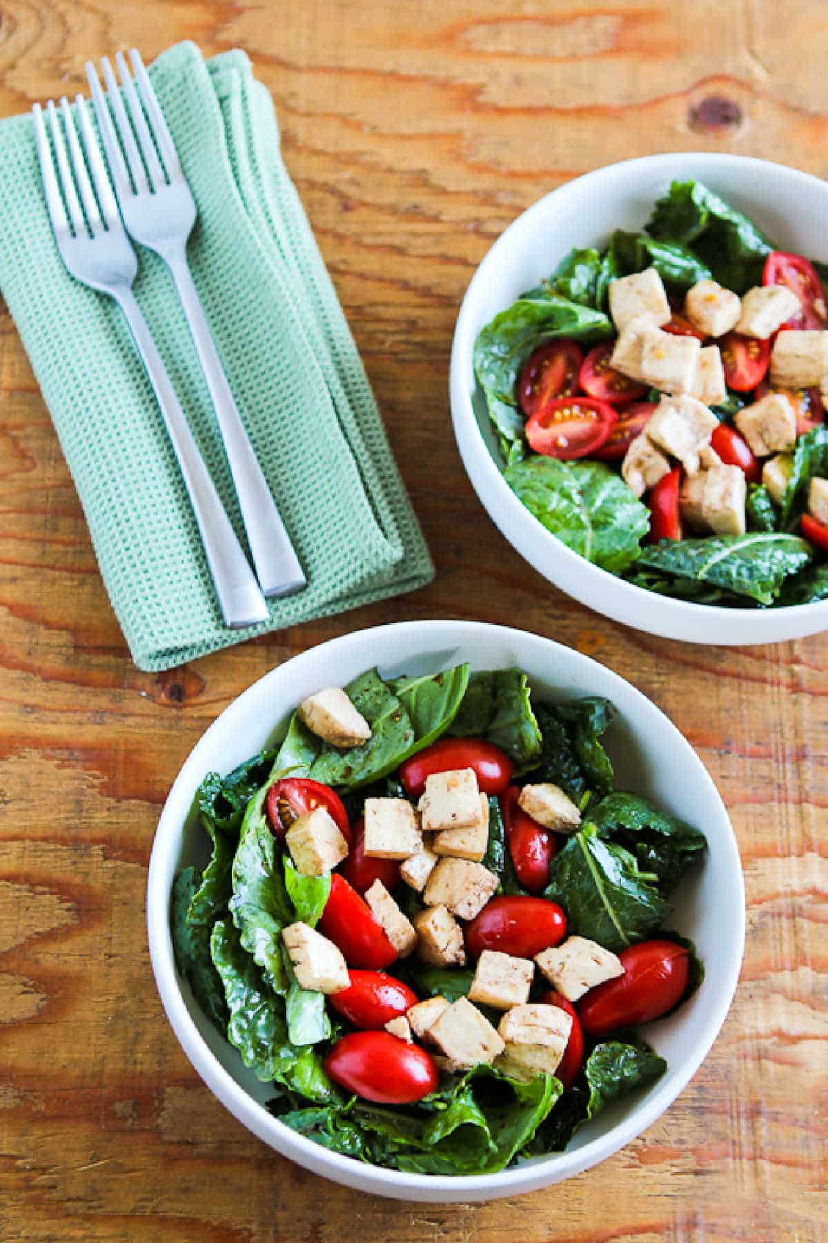 Baby Kale Caprese Salad in two serving bowls with forks and napkins