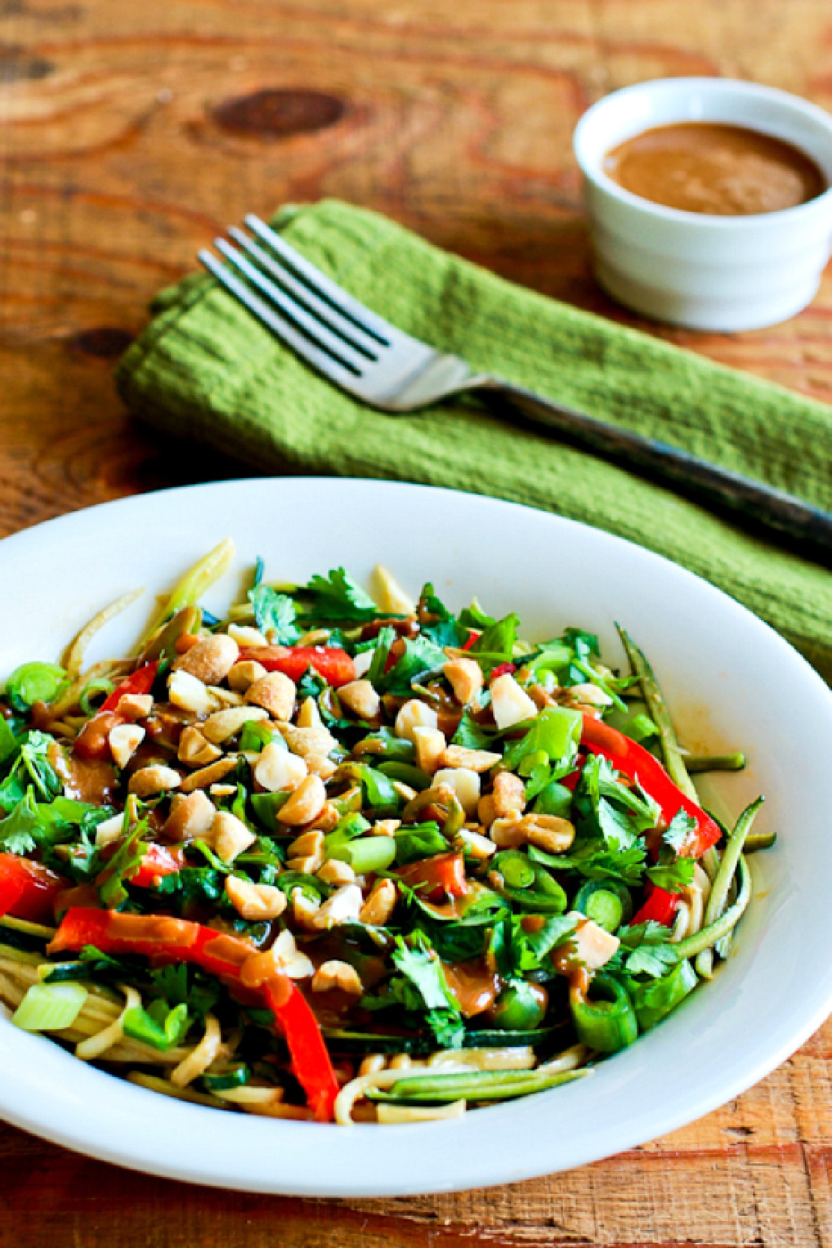 Zucchini Noodle Bowl with Peanut Sauce shown with sauce, fork, and napkin