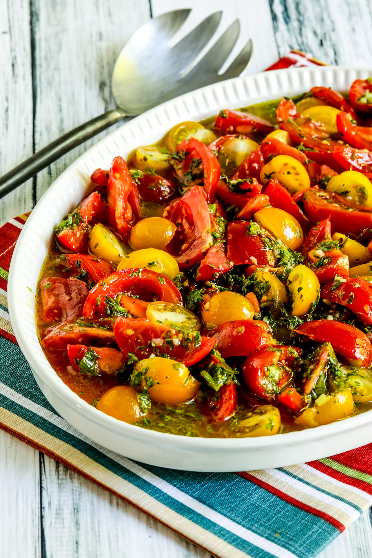 Marinated Tomatoes with Herb Dressing shown on serving dish with striped napkin