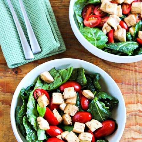 Baby Kale Caprese Salad shown in two salad bowls with forks and napkins