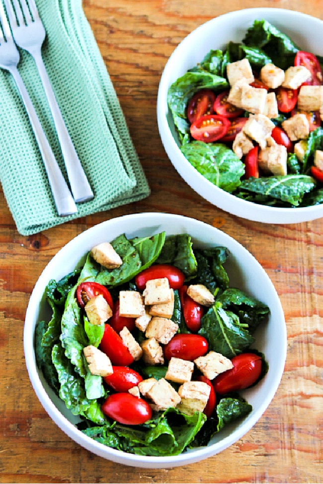 Baby Kale Caprese Salad shown in two salad bowls with forks and napkins