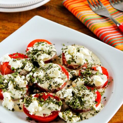 Summer Tomato Salad with Goat Cheese, Basil Vinaigrette, and Herbs close-up photo of finished salad on plate