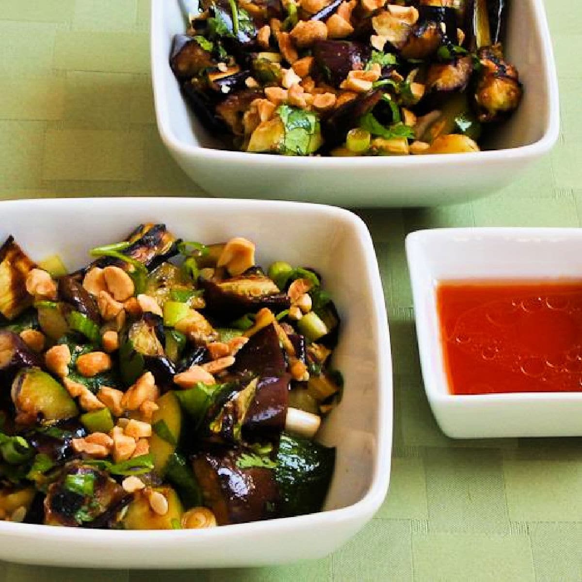 Square image for Thai Eggplant and Zucchini Salad shown in two serving bowls with spicy dressing.