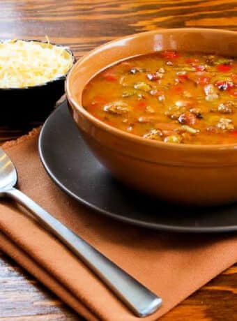 Square image for Slow Cooker Ground Turkey Soup shown in bowl with grated cheese in back.