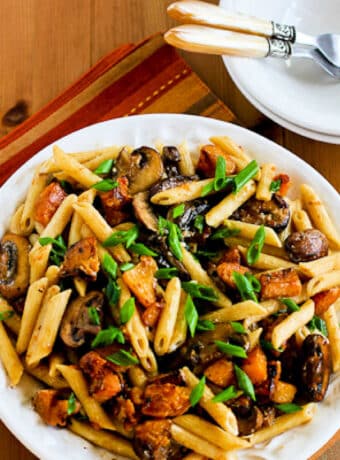 Pasta with Butternut Squash shown on serving plate with forks, plates in back.
