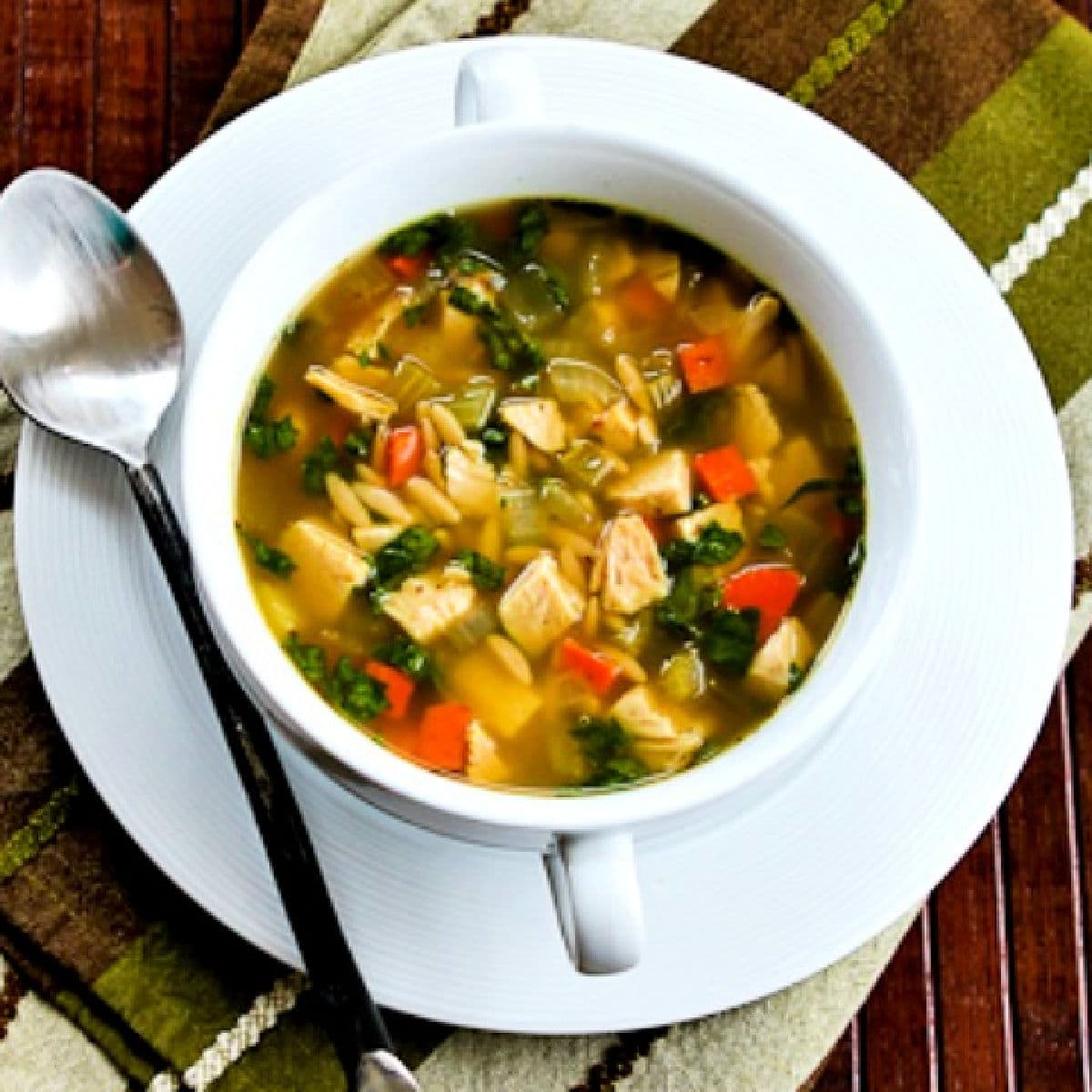 Square image for Slow Cooker Turkey Soup with Spinach and Lemon shown in bowl with plate and spoon.