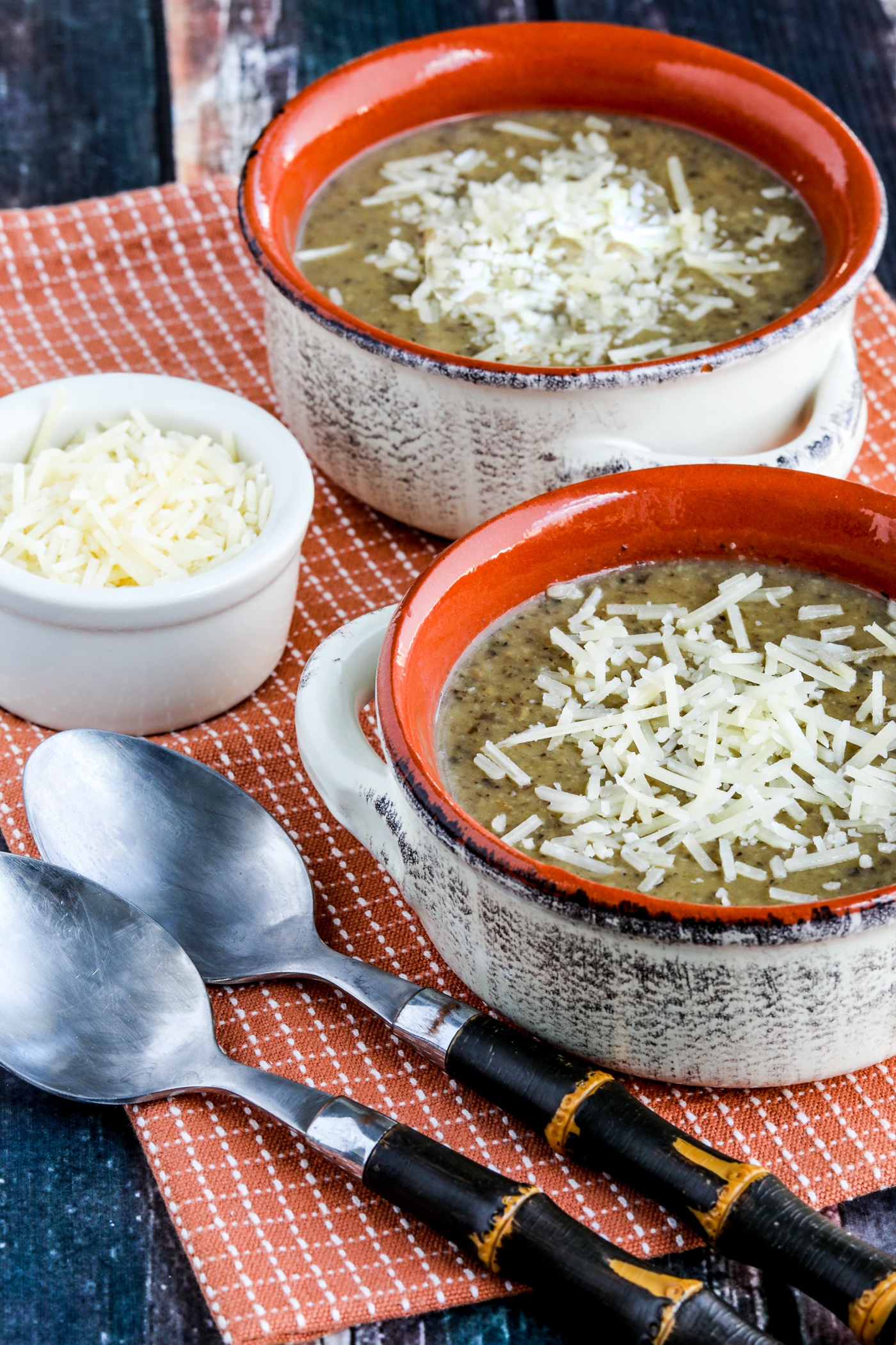 Instant Pot Cauliflower Mushroom Soup shown in two soup bowls with spoons and Parmesan Cheese 