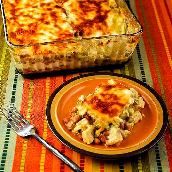 Layered Mexican Casserole with Chicken, Chiles, Pinto Beans, and Cheese finished casserole with one serving on plate