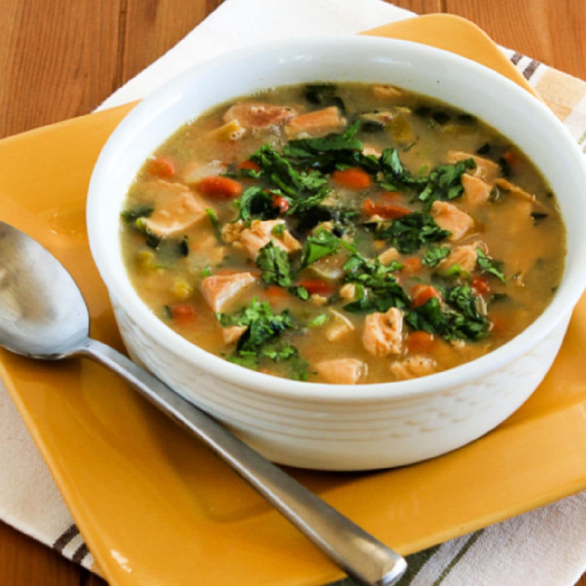Square image of Mexican Chicken Soup shown in bowl with spoon, garnished with chopped fresh cilantro.