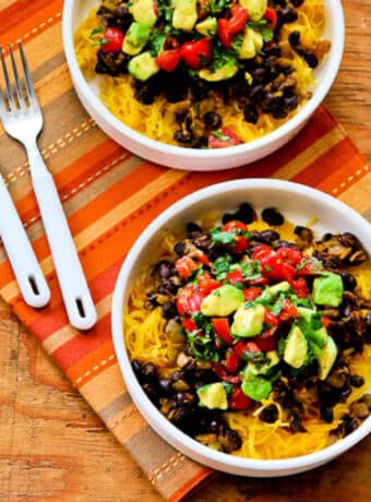 Spaghetti Squash Burrito Bowl shown in two bowls with forks on colorful napkin.