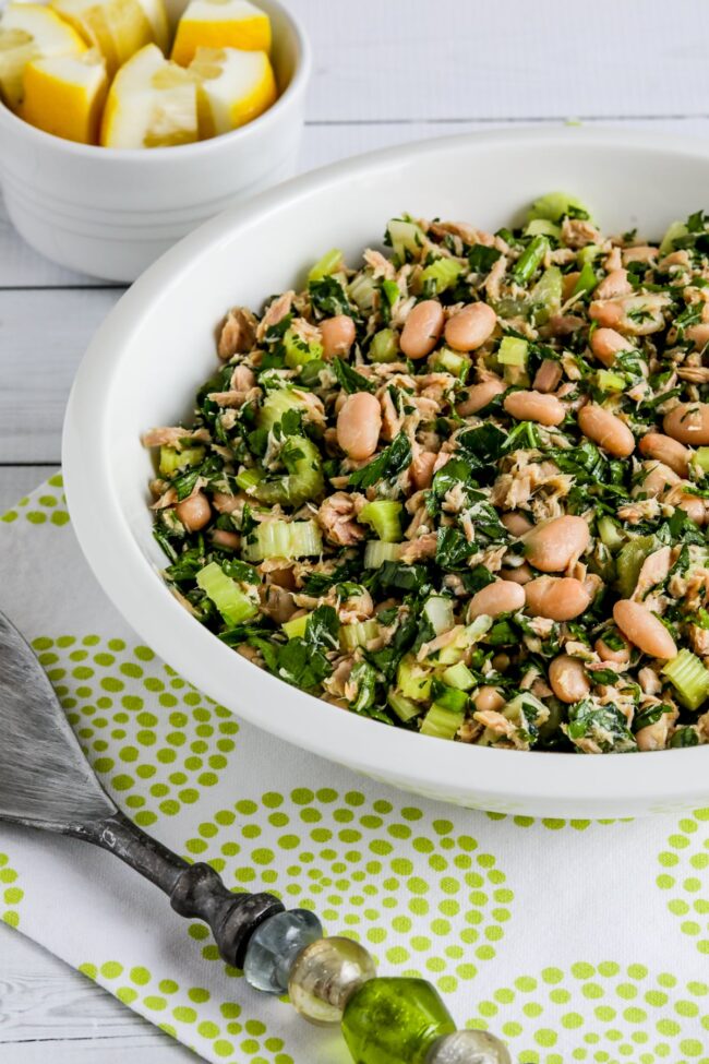 Tuna White Bean Salad shown in serving bowl with salad spoon on green-white napkin.