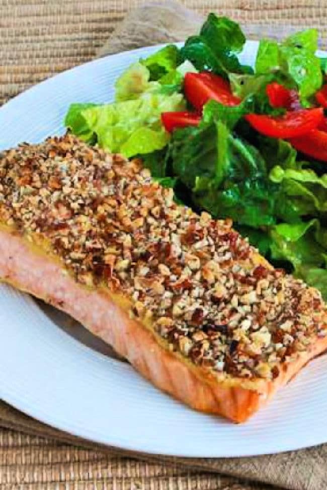Pecan Crusted Salmon shown on plate with lettuce and tomato salad.