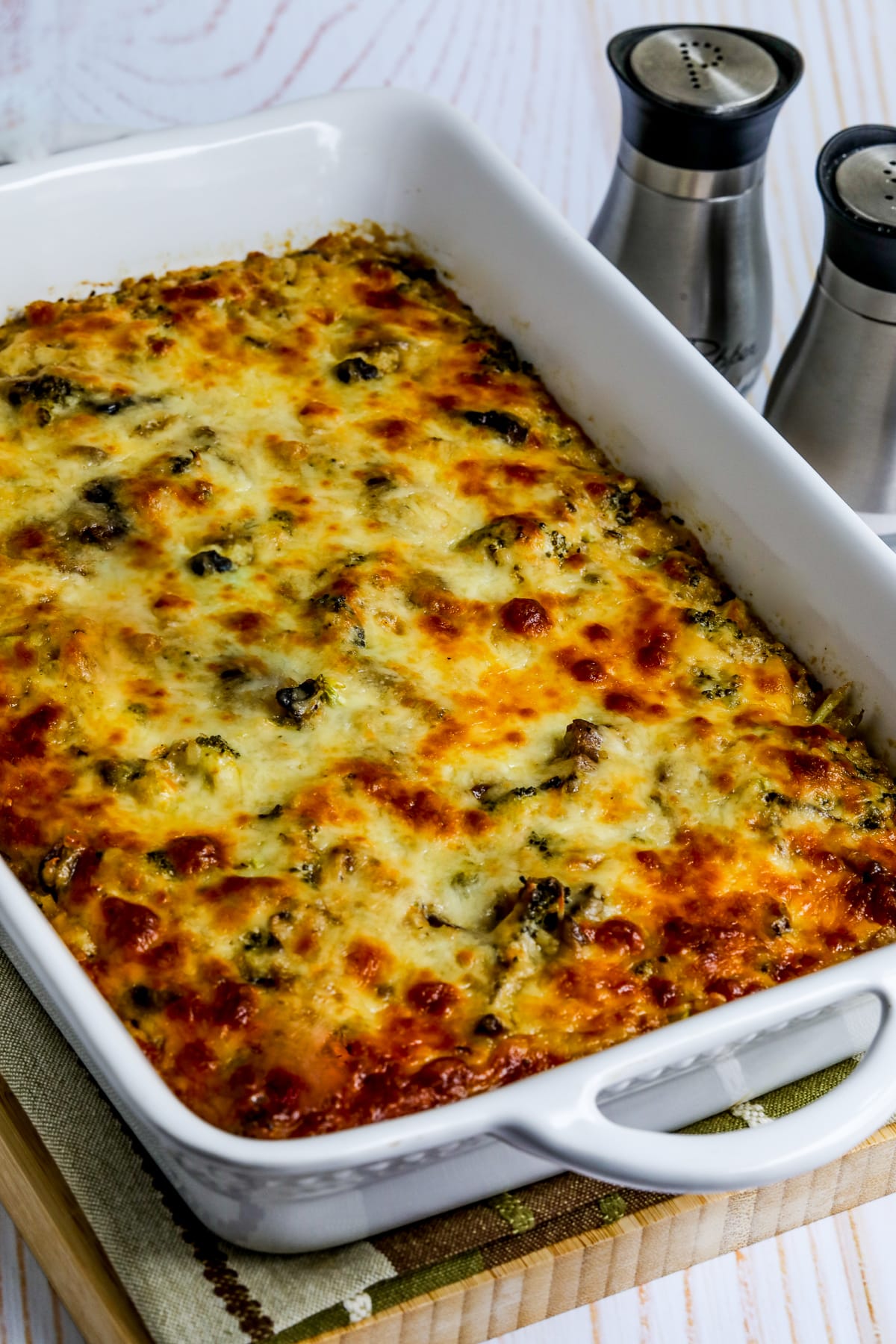 Cheesy Vegetarian Casserole (with Cauliflower Rice) shown in baking dish with salt and pepper in back.