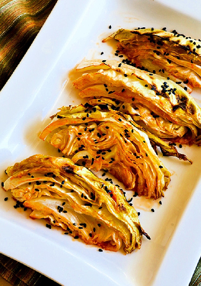 Close-up of Roasted Cabbage with Lime and Sriracha on baking sheet with black sesame seeds