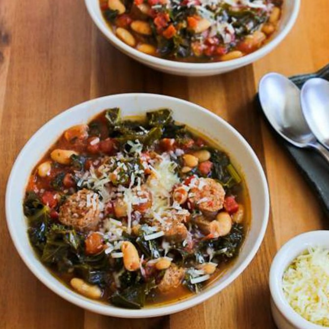 Slow Cooker Stew with Sausage, Beans, and Kale in two bowls with Parmesan