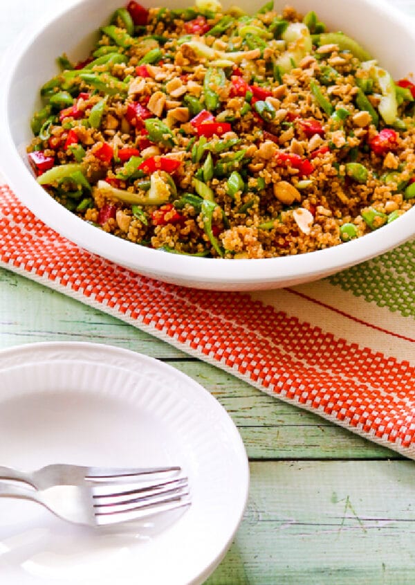 cropped image of Asian Quinoa Salad in serving bowl with plates and forks