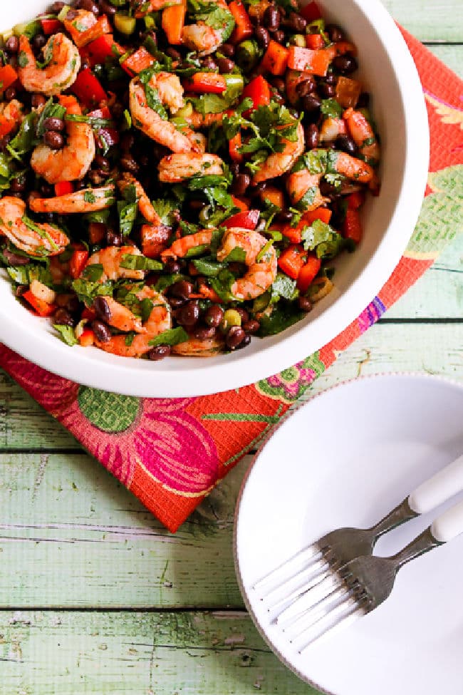 Shrimp and Black Bean Salad in serving bowl with plates, forks.