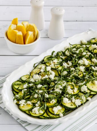 Close-up photo of Zucchini Carpaccio on serving plate with lemon slices in background