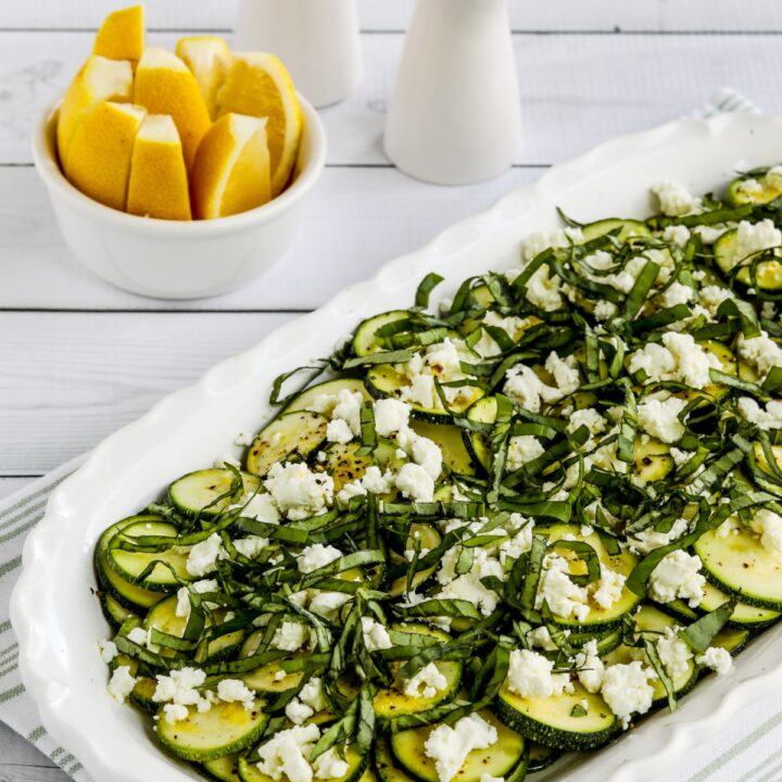 Close-up photo of Zucchini Carpaccio on serving plate with lemon slices in background