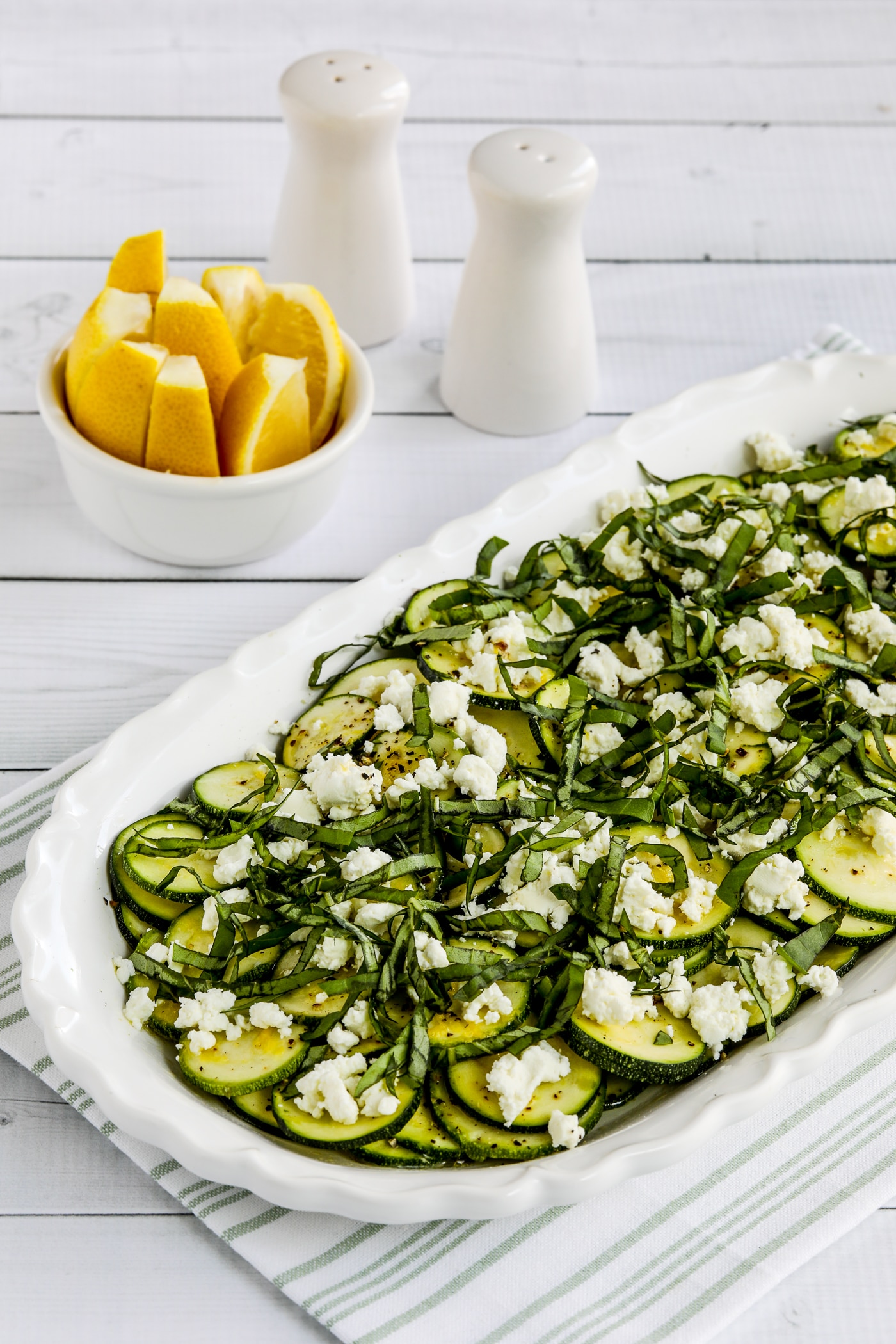 Close-up photo of Zucchini Carpaccio on serving plate with lemon slices in background