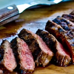 Grilled Cuban Flank Steak shown on cutting board with carving fork and knife