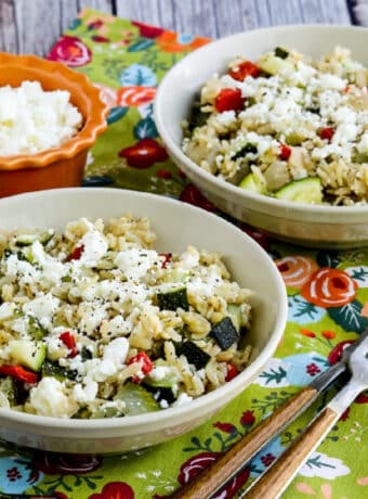 Square image of Slow Cooker Brown Rice with Veggies and Feta shown in two serving bowls.