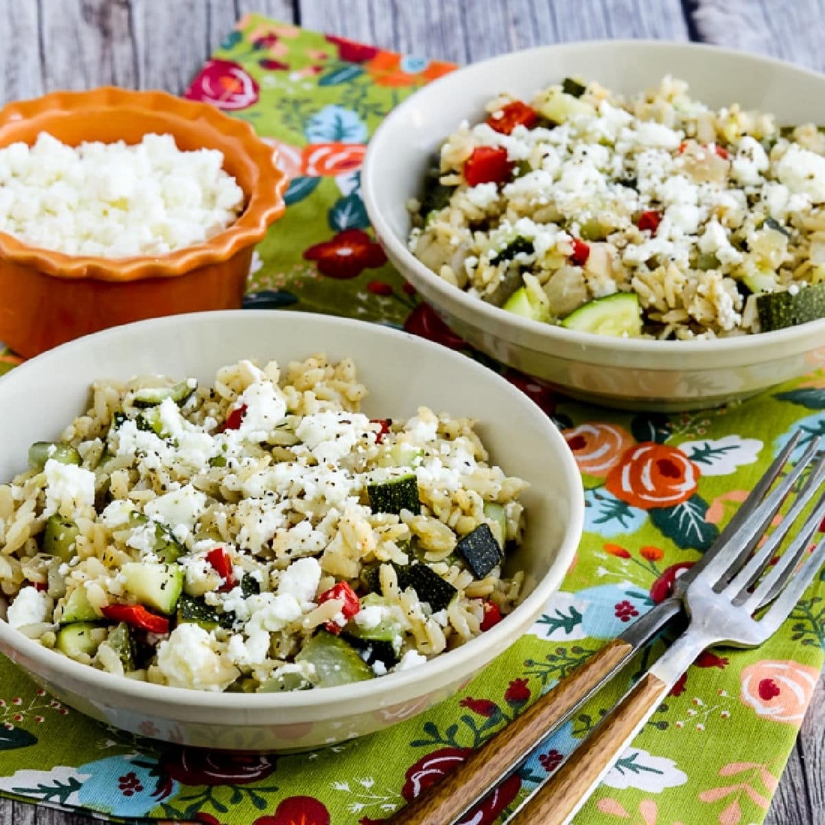 Square image of Slow Cooker Brown Rice with Veggies and Feta shown in two serving bowls.