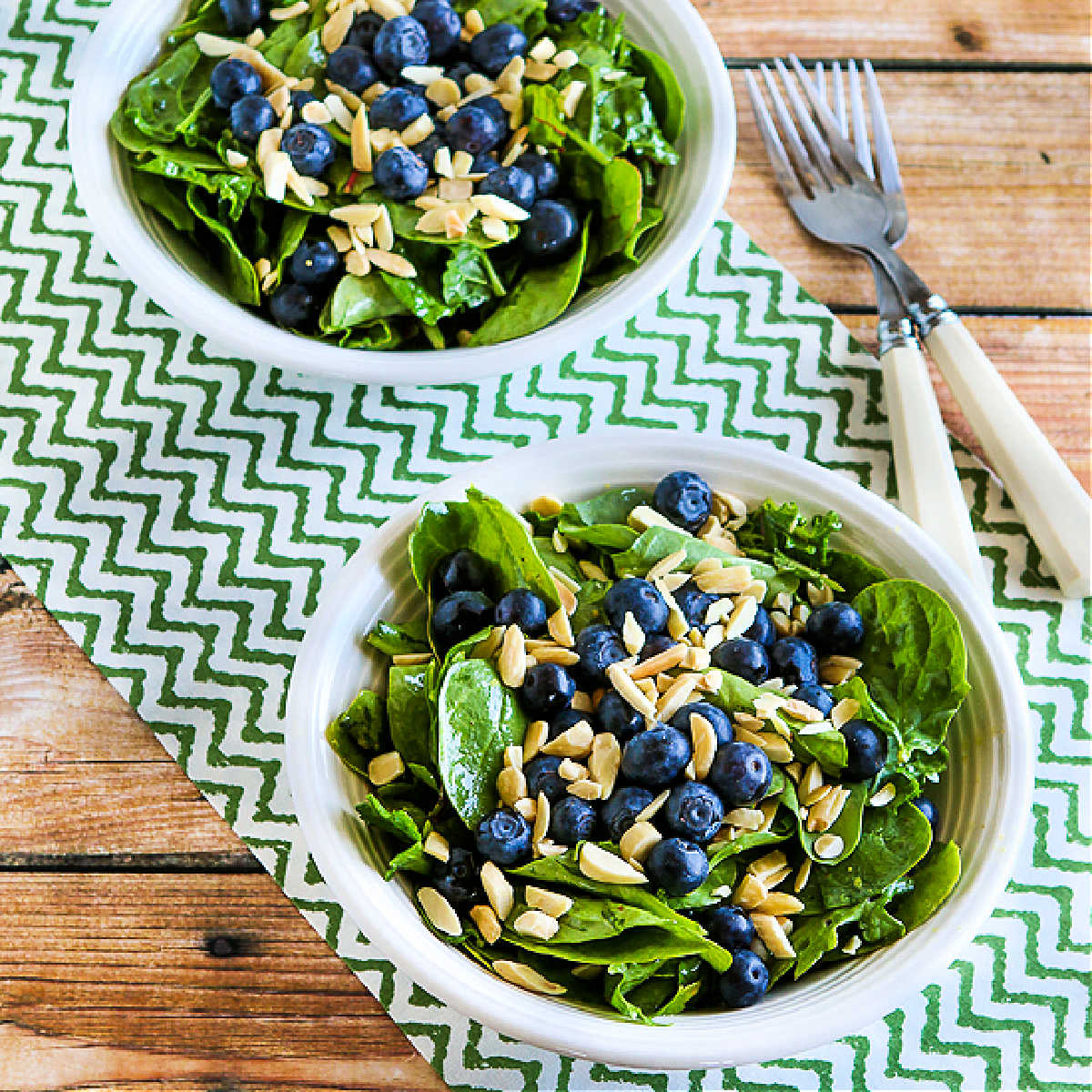 Square image of Power Greens Salad with Blueberries in two serving bowls.