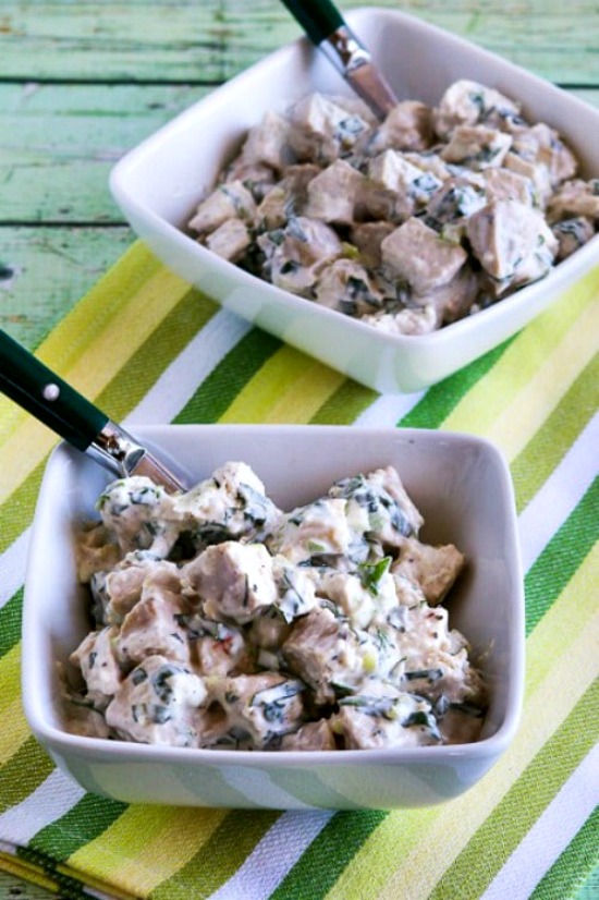 Chicken Salad with Basil shown in two serving bowls with forks and napkin