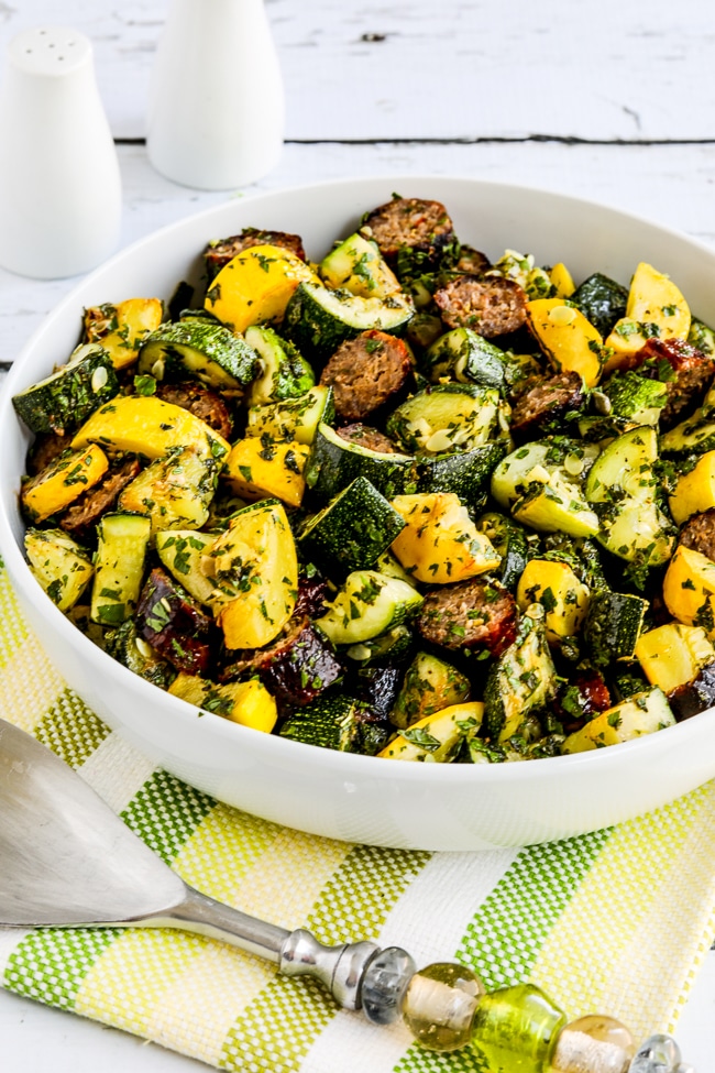 Grilled sausage and summer squash with lemon and herbs is a finished dish in a serving bowl