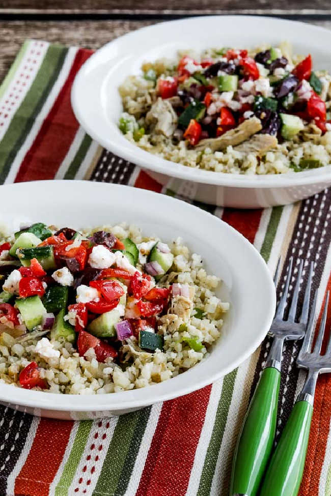 Slow Cooker Cauliflower Rice Greek Chicken Bowls shown in two bowls with green forks