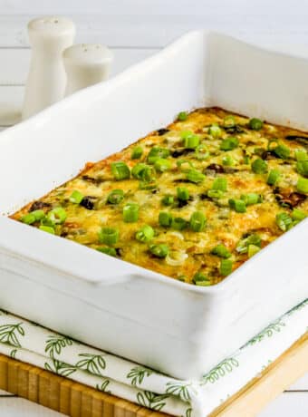 Square image for Cheesy Vegetarian Breakfast Casserole shown in baking dish on napkin and cutting board.