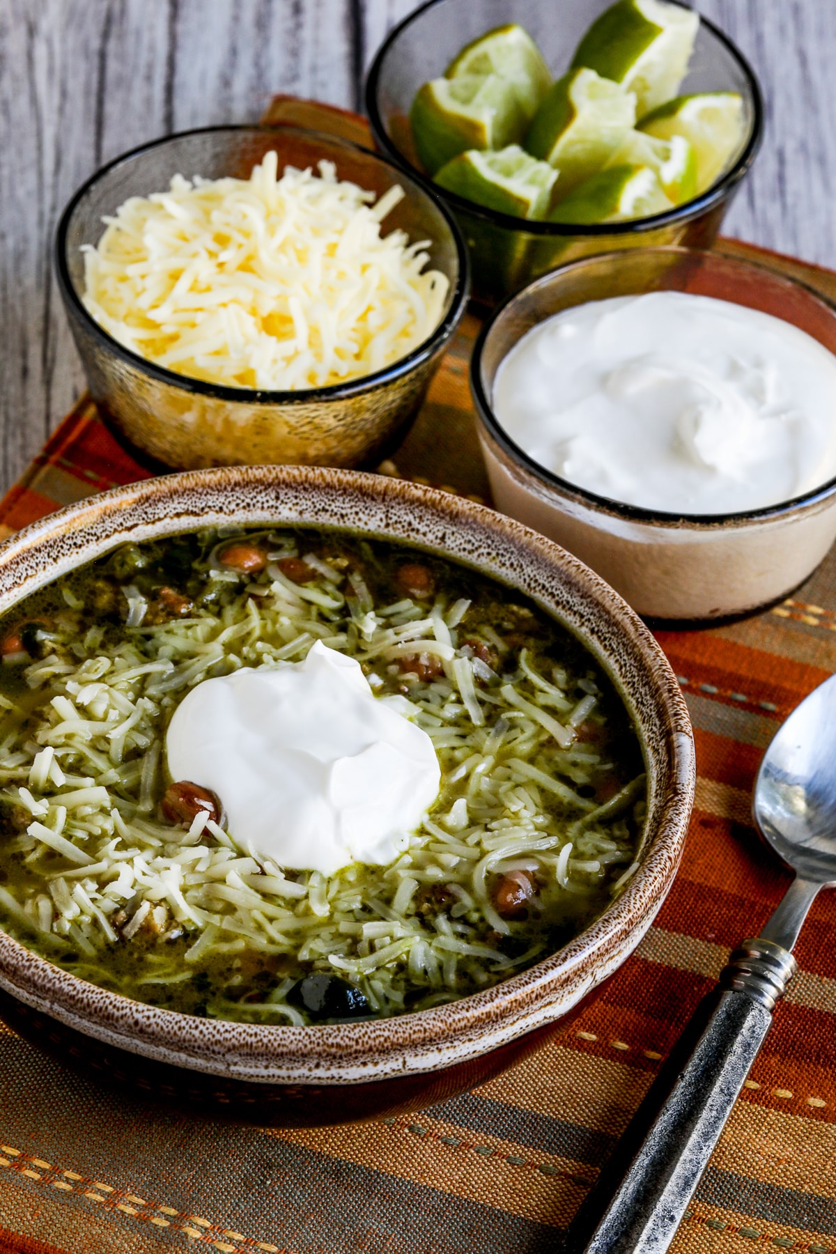 Turkey Pinto Bean Chili shown in serving bowl with cheese and sour cream