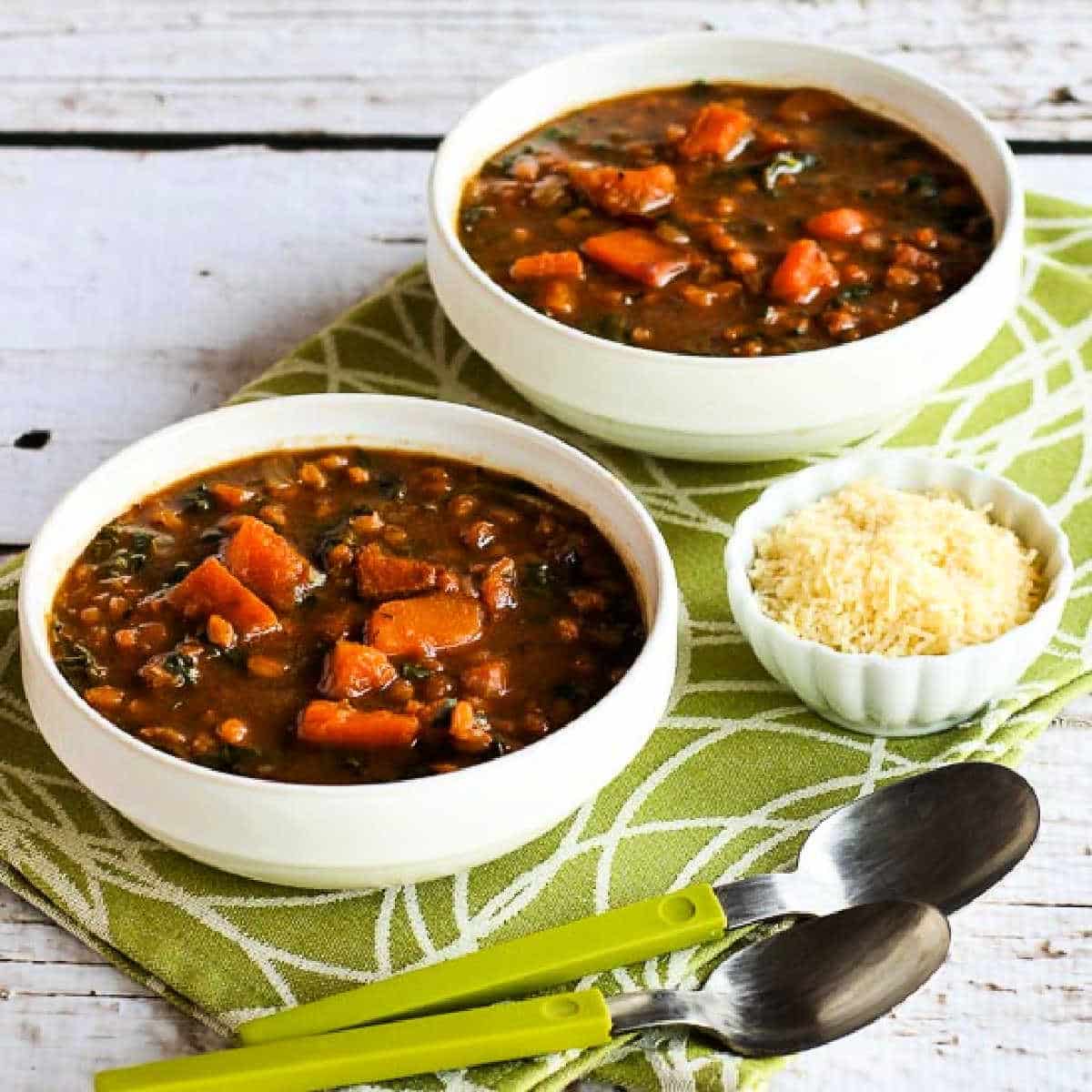 Square image for Butternut Squash Kale Soup shown in two bowls with spoons.