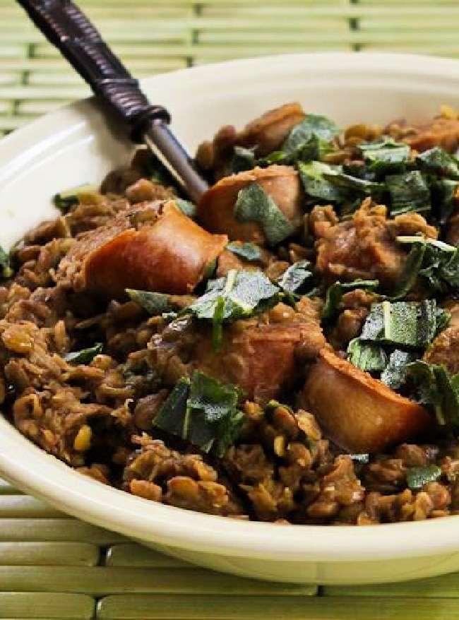 Cropped image of Sausage and Lentils with Fried Sage shown in serving bowl with fork.