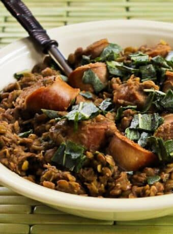 Sausage and Lentils with Fried Sage shown in serving bowl with fork.