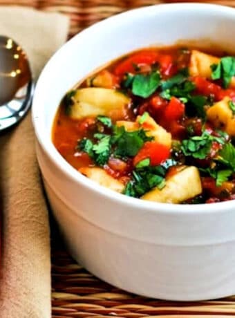 Square image for Spicy Red Fish Stew shown in serving bowl with orange spoon.