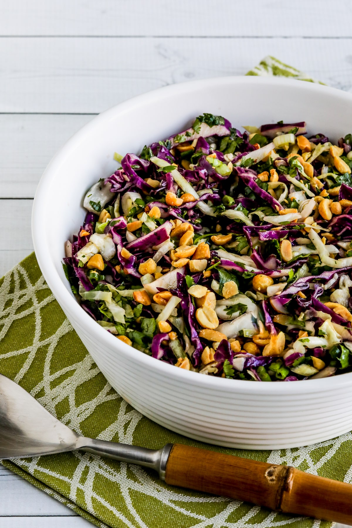 Thai Cabbage Salad in white bowl with serving spoon.