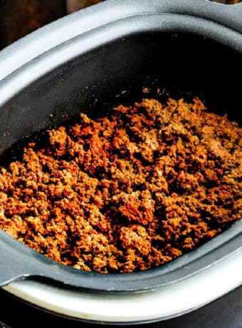 Square image of Slow Cooker Taco Meat with cooked meat shown in slow cooker.