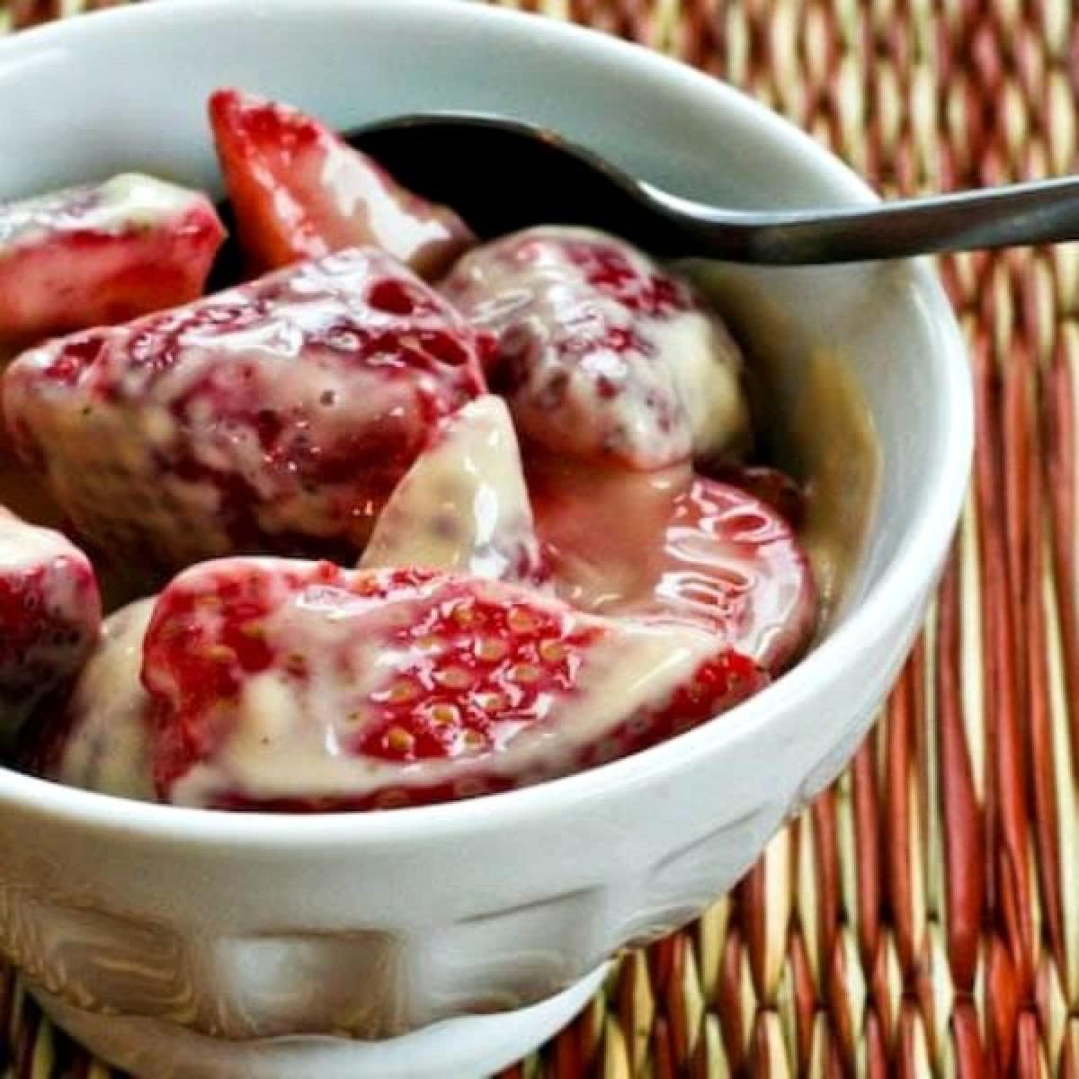 Square image of Strawberries Romanoff shown in serving dish with spoon.