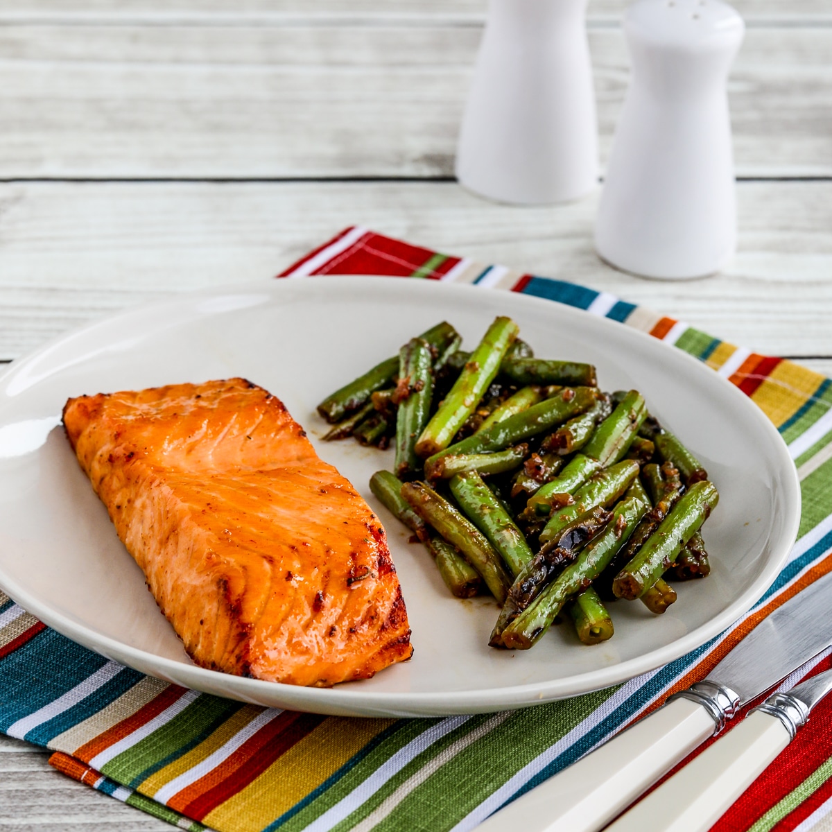 Maple Glazed Salmon square image on serving plate with green beans, silverware, and napkin