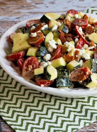 Raw Zucchini Salad with Bacon, Tomato, and Feta shown in serving bowl on napkin.