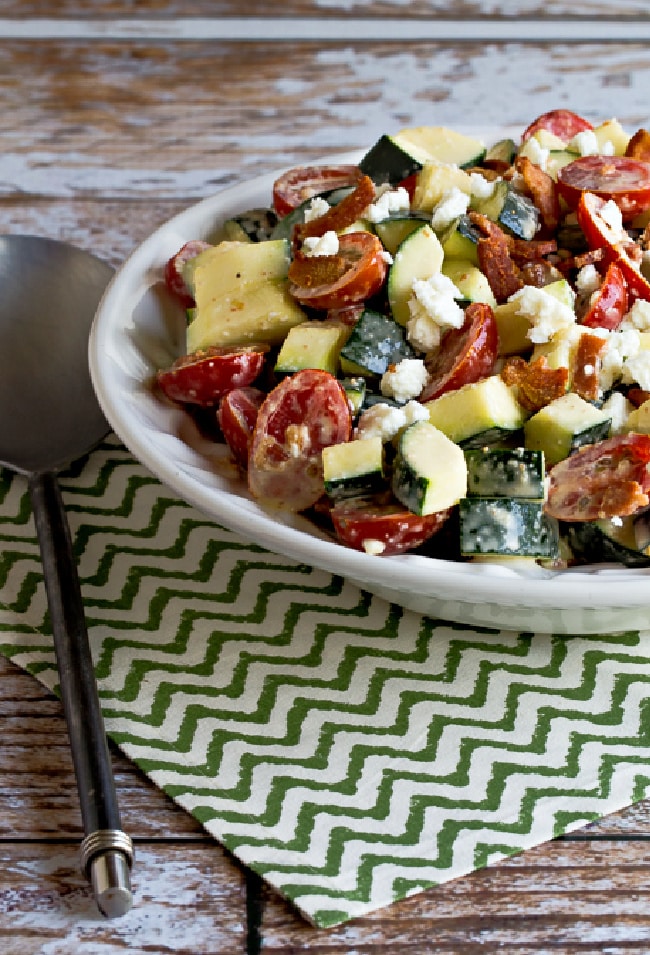 Bacon, Tomato, and Zucchini Salad with Feta shown on serving plate on green-white napkin