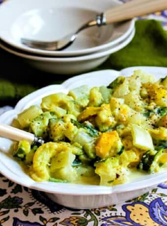Mom's Creamed Zucchini shown in serving dish with bowls in back.