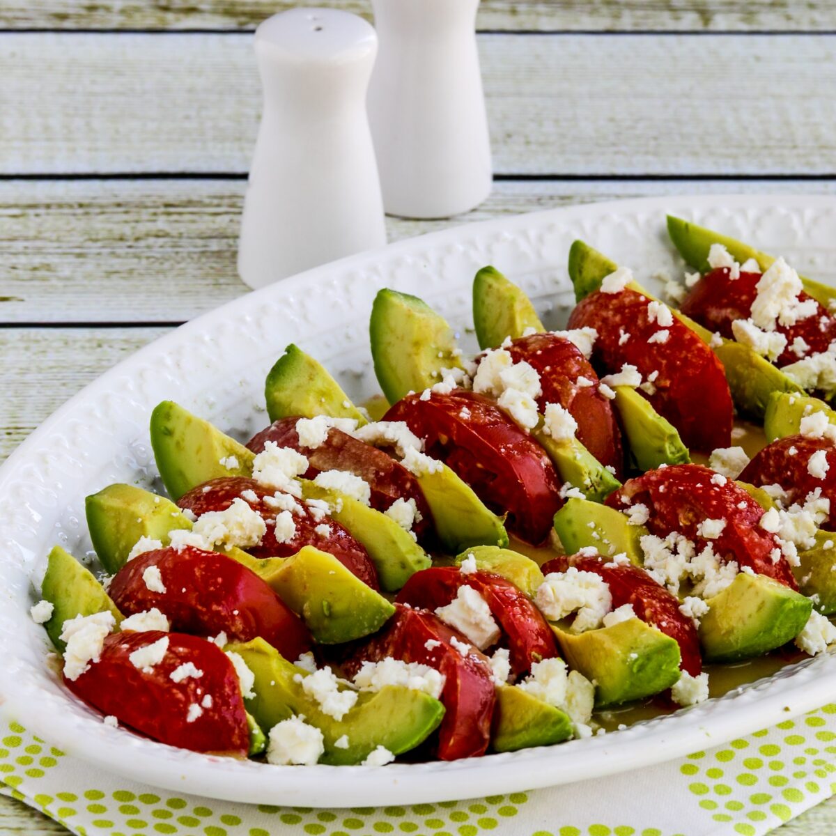 Avocado Tomato Salad on serving plate with salt-pepper in back.
